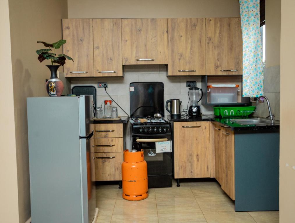 a kitchen with wooden cabinets and a refrigerator at Edrin Apartments in Kampala