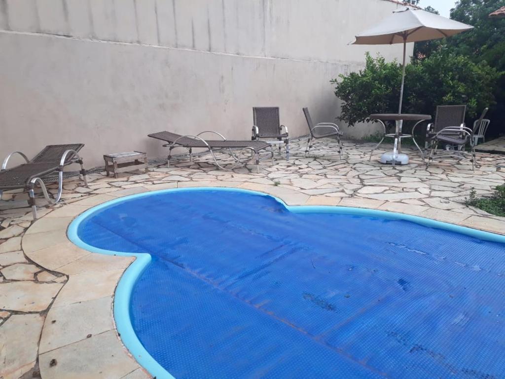 een blauw zwembad met stoelen en een parasol bij Casa Cachoeira Tororó in Brasilia