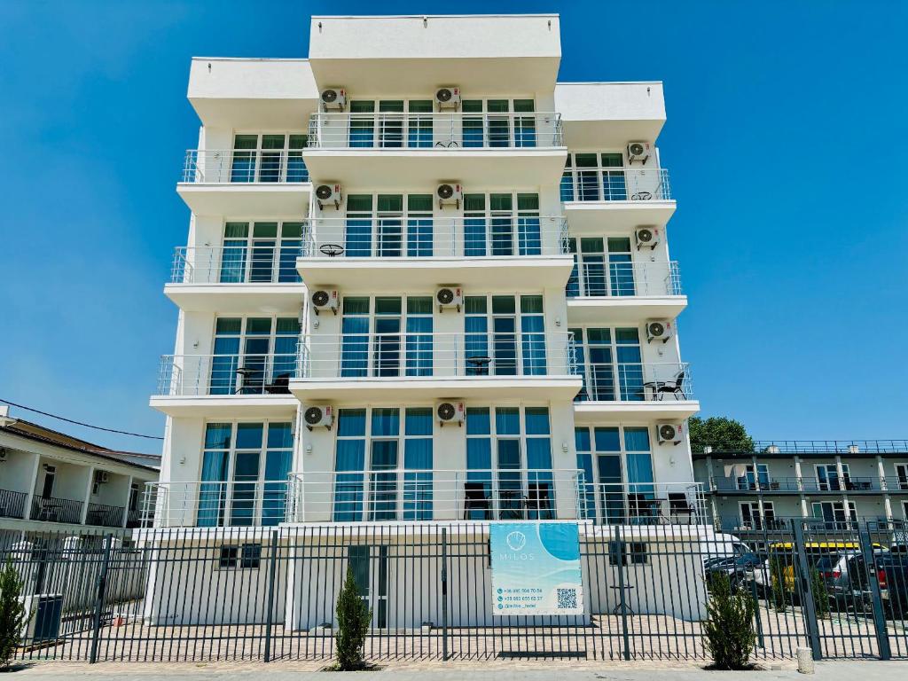 a white building with a fence in front of it at Milos Hotel in Zatoka