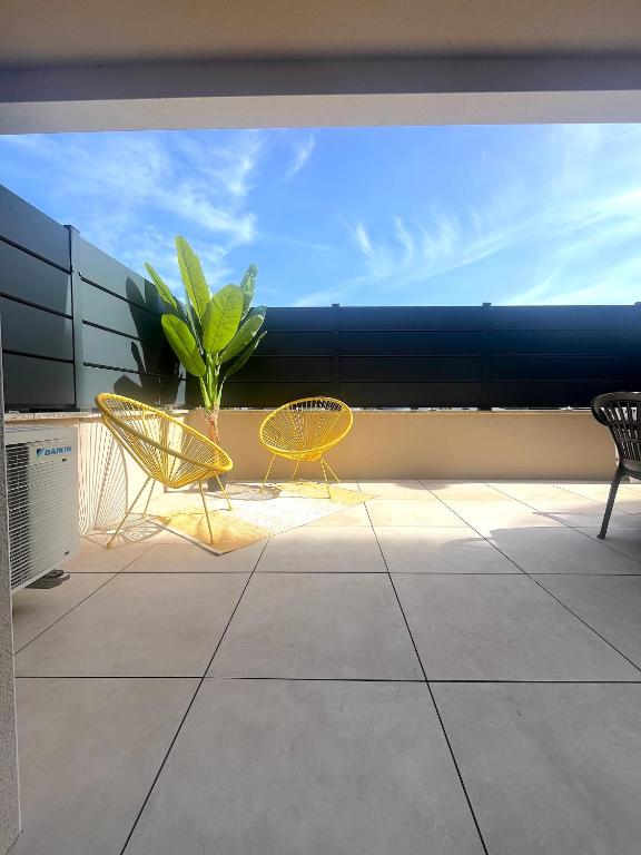 2 chaises jaunes et une plante sur un balcon dans l'établissement Agosta Porticcio - Plage à 200m - T2 SUN entre mer & maquis - Barbecue- rés Fiore di maghja - PARKING - Wifi - 4 Pers, à Les Hameaux de Porticcio