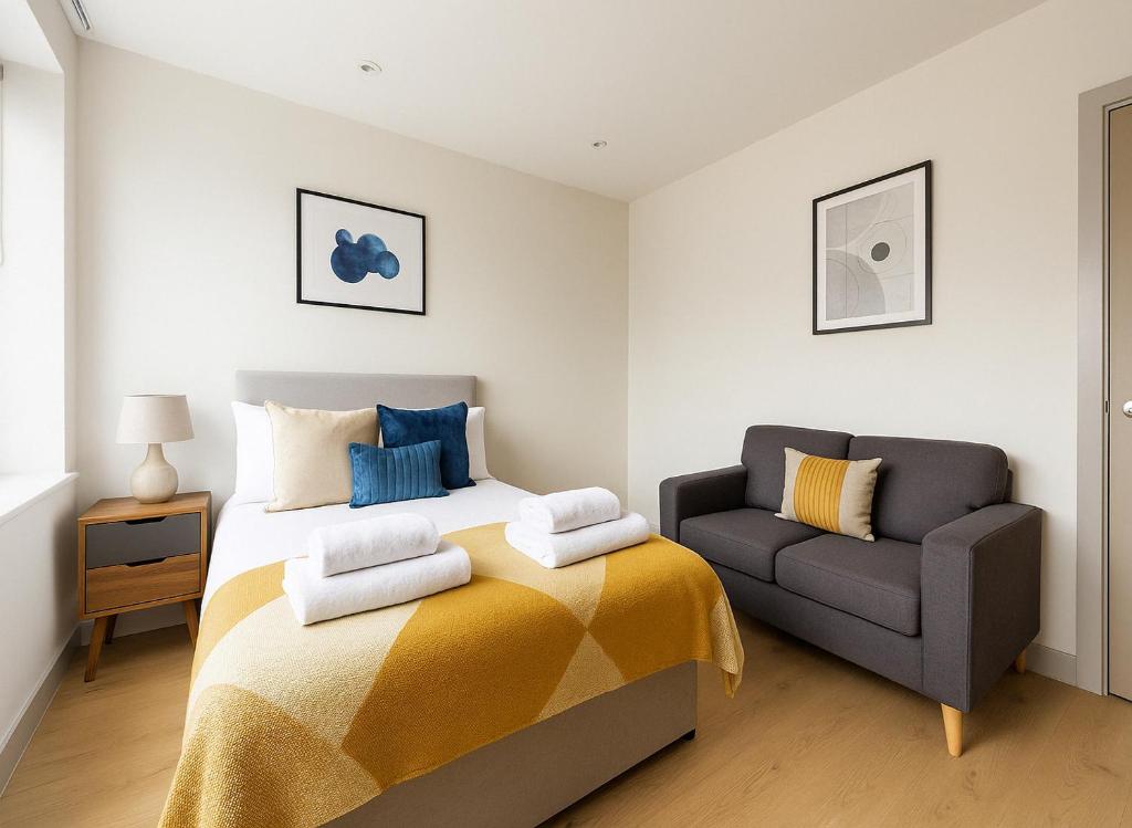 a bedroom with a bed and a couch at Bright Studio Flat - Walk to River Thames & Kingston Town in Surbiton