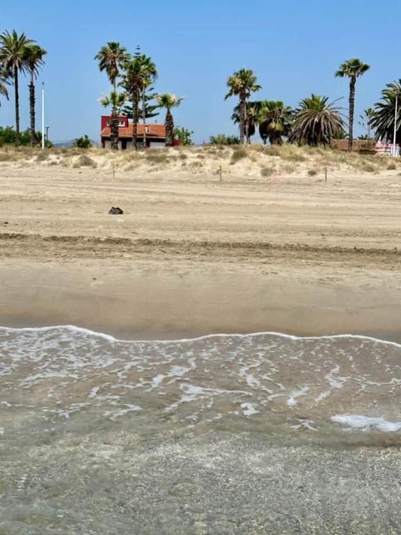 a sandy beach with palm trees in the background at Villa Grao Benicasim REF 026 in Grao de Castellón