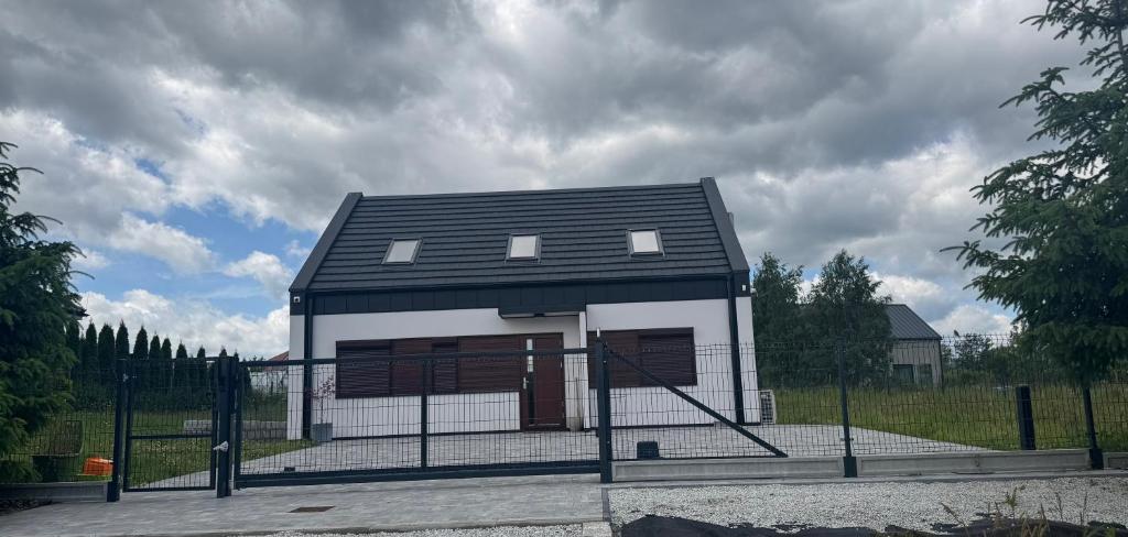 a small house with a black roof and a fence at Dom z widokiem in Miszkowice