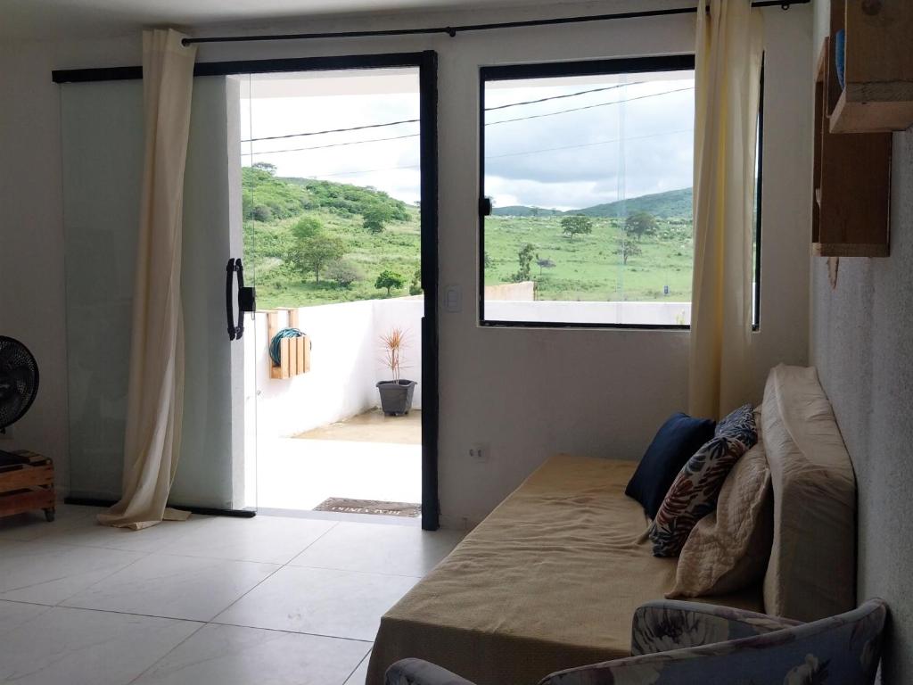 a living room with a couch and a sliding glass door at Vila Negreiros Serra Negra Casa 4 in Bezerros