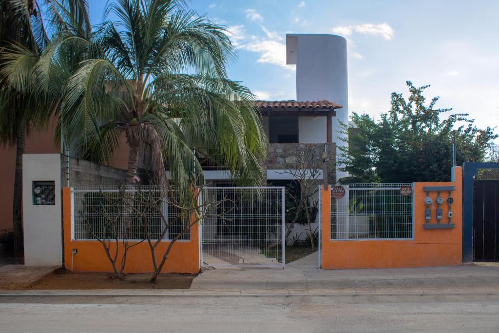 an orange gate in front of a house with a palm tree at Departamento Ninfa "Alojamiento Completo" in Puerto Escondido