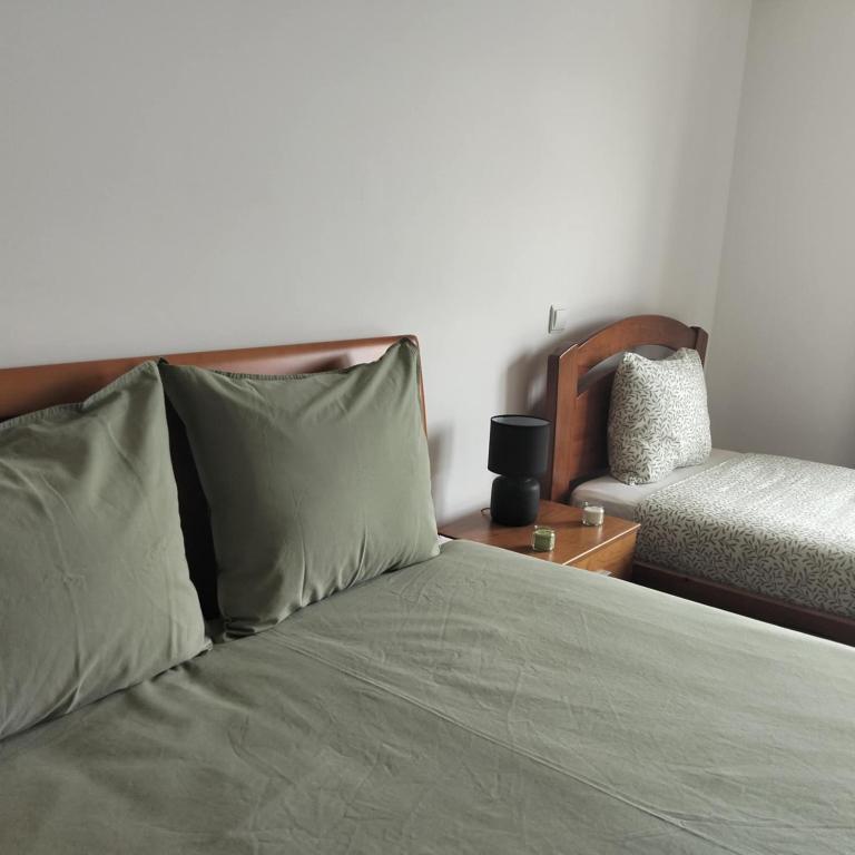 a bed with green pillows and a nightstand with a bed sidx sidx sidx at Quartos, Solar da São in Nazaré