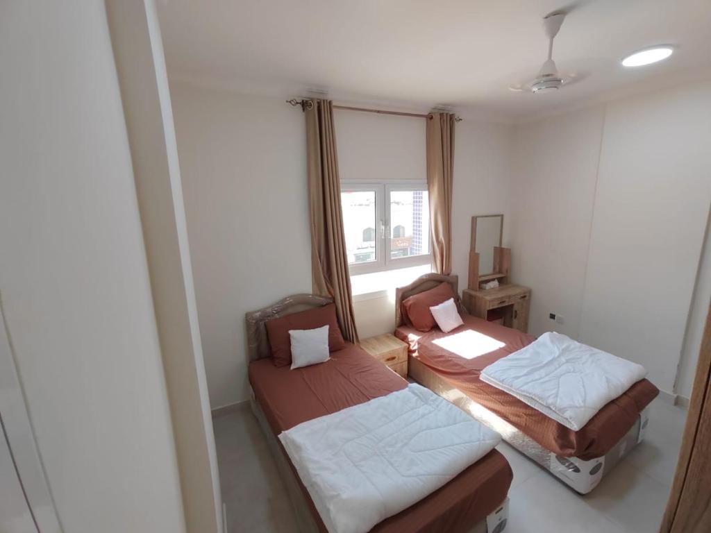 two beds in a small room with a window at Al Anwar Building Luxury in Salalah