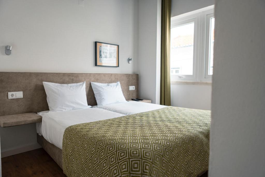 um quarto com uma cama e uma janela em Casa das Aguarelas na Ericeira