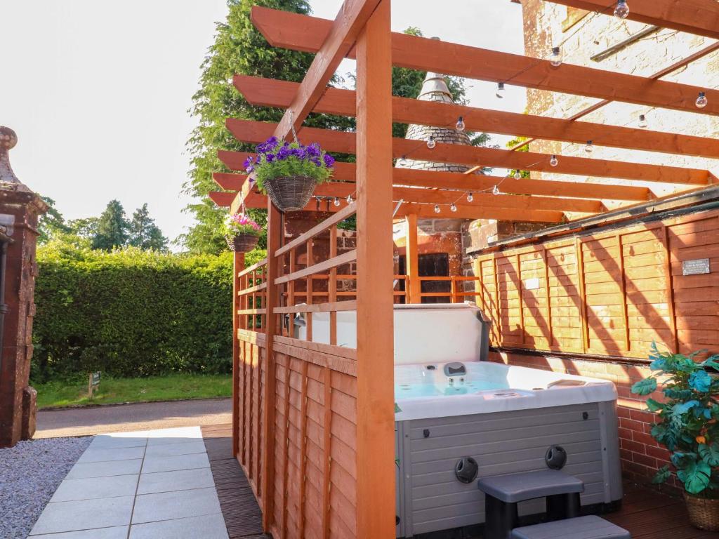 a hot tub on a patio with a wooden pergola at Rob Roy Apartment in Stirling