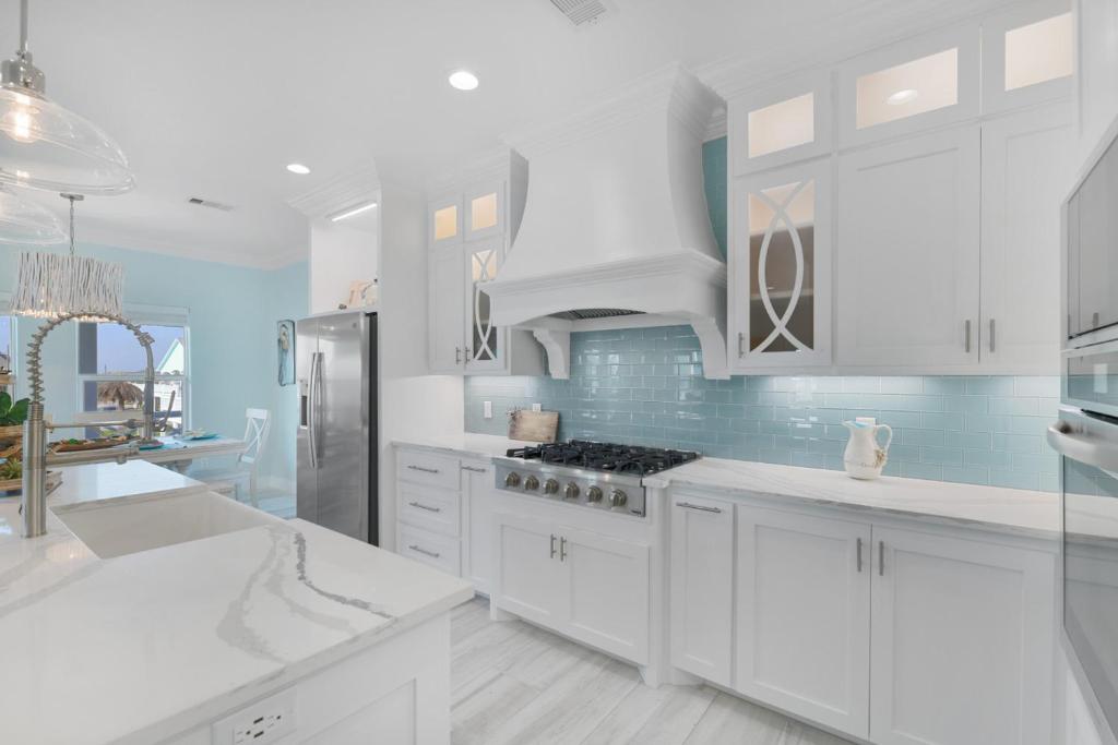 a white kitchen with blue walls and white cabinets at Near Beach Large Home Sleeps 22 BBQ Soaking Tub in Bolivar Peninsula