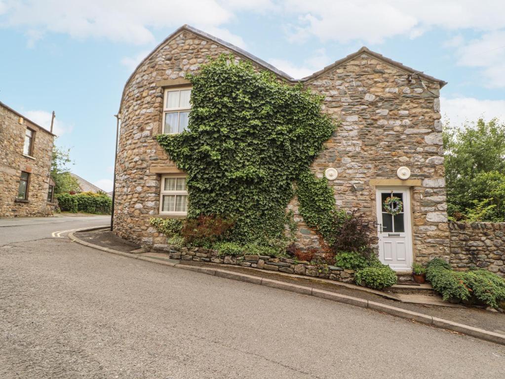 a stone house with ivy growing on the side of it at Corner Cottage in Carnforth