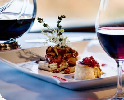 a plate of food and a glass of wine on a table at Auberge du Lac Morency in Saint-Hippolyte
