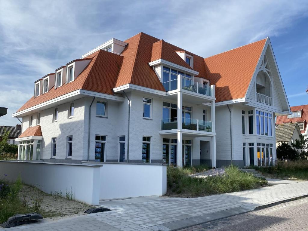 a large white house with a brown roof at Casa del Rops, luxury apartment, two bathrooms and roof terrace, near the beach in Cadzand