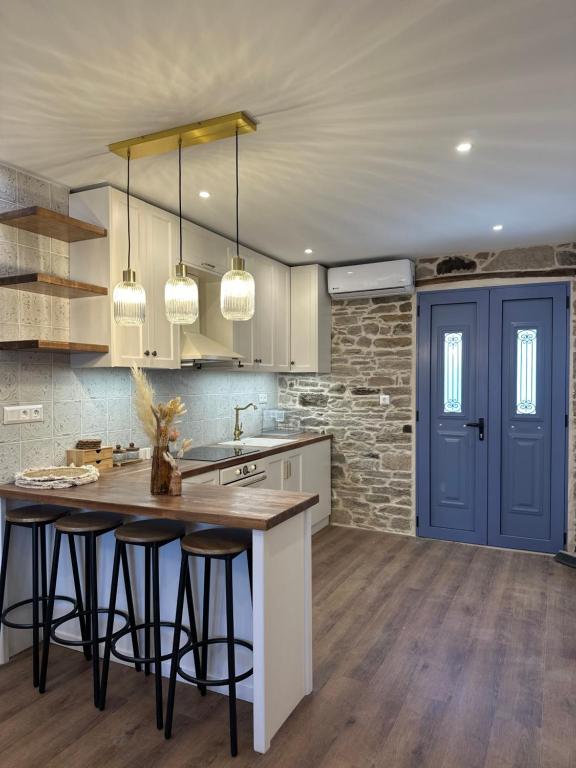 a kitchen with a island with bar stools and a blue door at Theros Retreat in Káspakas