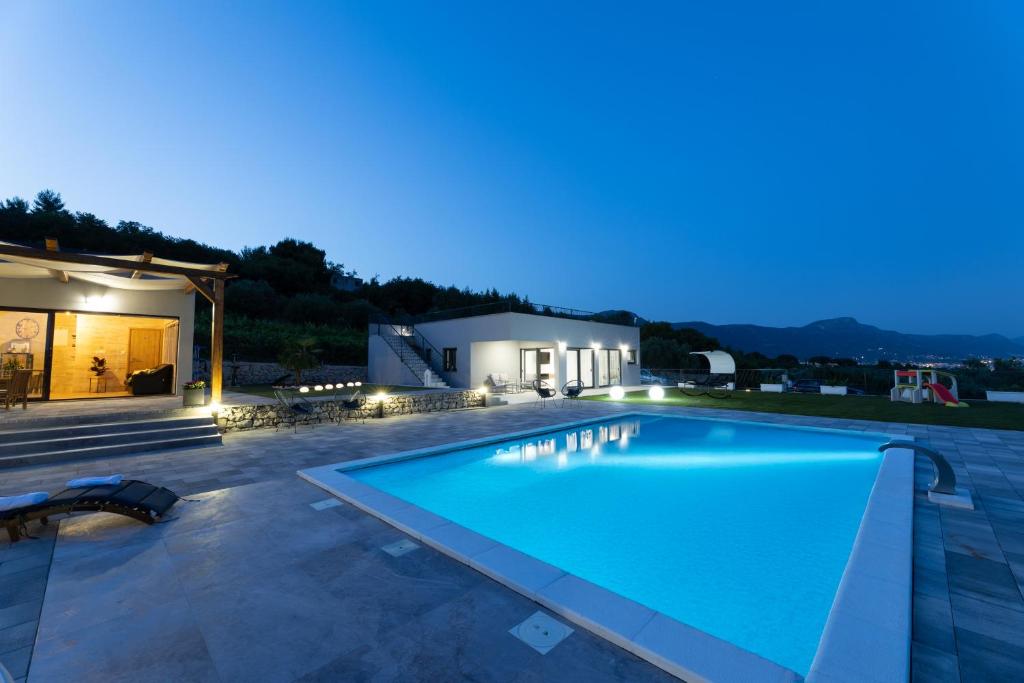 a swimming pool at night with a house at Villa Bijaći in Kastel Novi