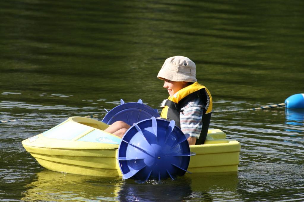 a young boy sitting in a paddle boat in the water at Auberge du Lac Morency in Saint-Hippolyte