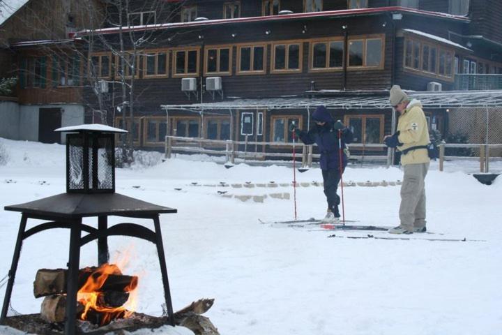 two people on skis standing around a fire in the snow at Auberge du Lac Morency in Saint-Hippolyte