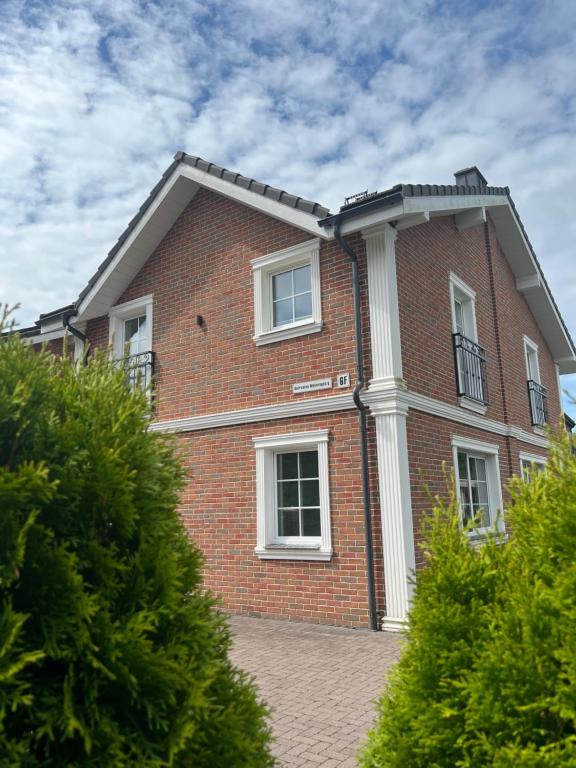 a red brick building with a white pillar at Melnrage Beach cozy apartments & terrace - pine view sea entry in Klaipėda