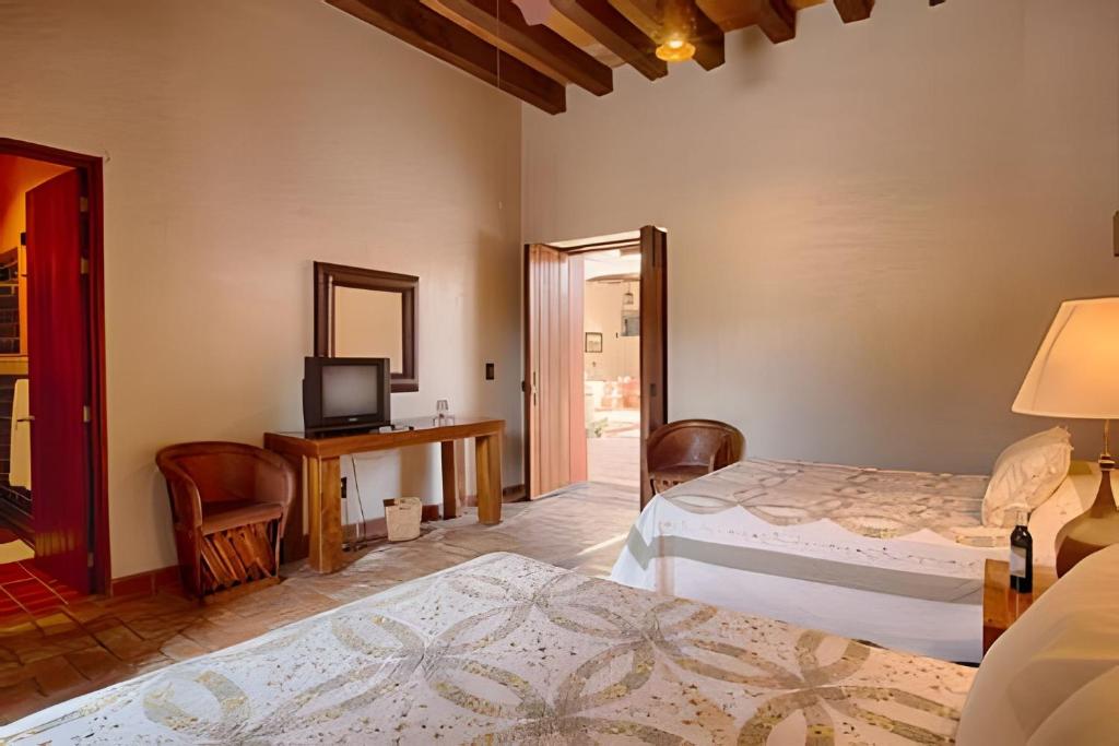 a hotel room with two beds and a television at Hermosa y amplia casona en Mascota, +16 personas in Mascota