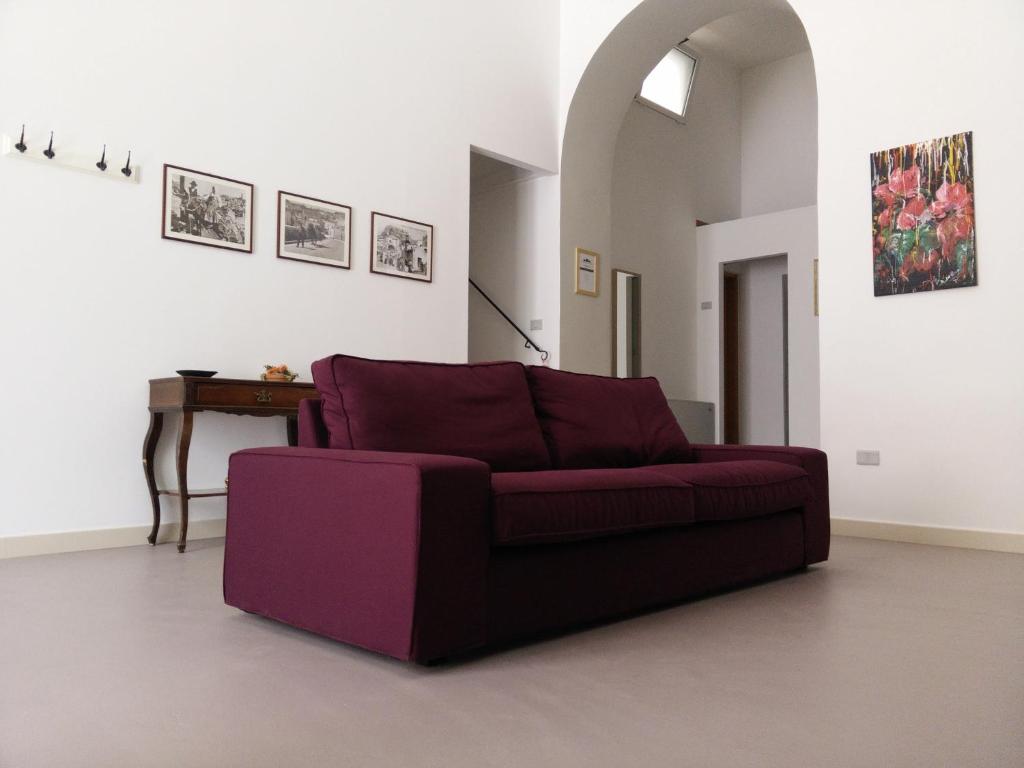 un sofá púrpura en una sala de estar con mesa en B&B Il Tramontano, en Matera