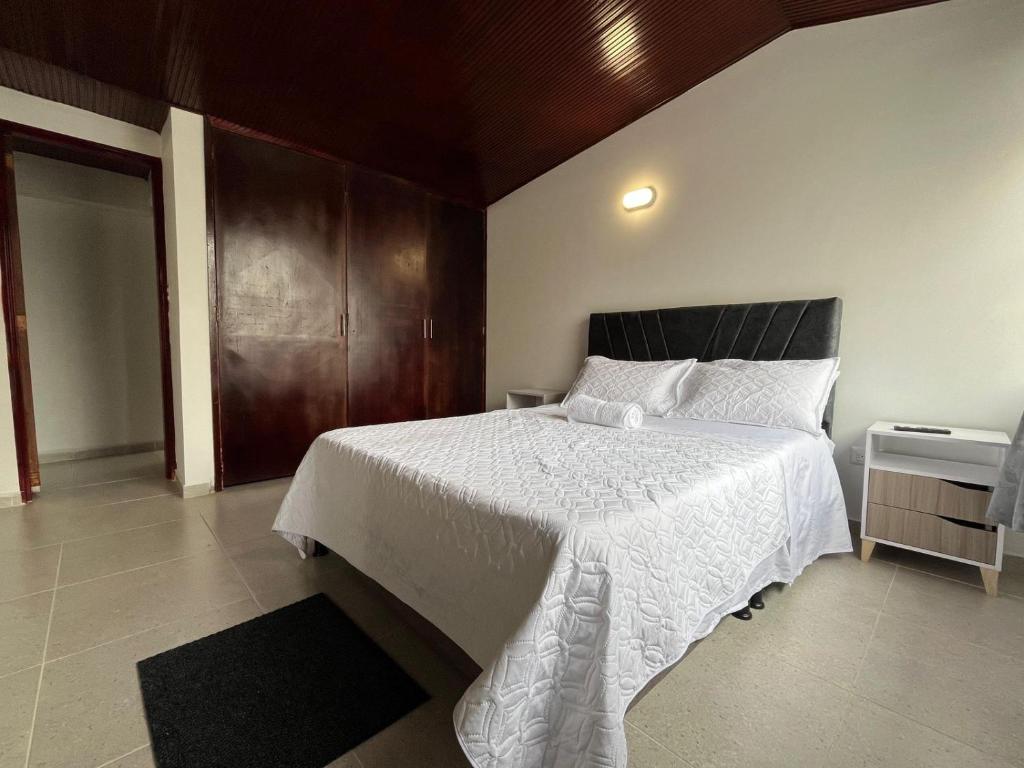 a bedroom with a white bed with a wooden ceiling at Casa Hotel Pontevedra - cerca a la clínica Shaio, in Bogotá