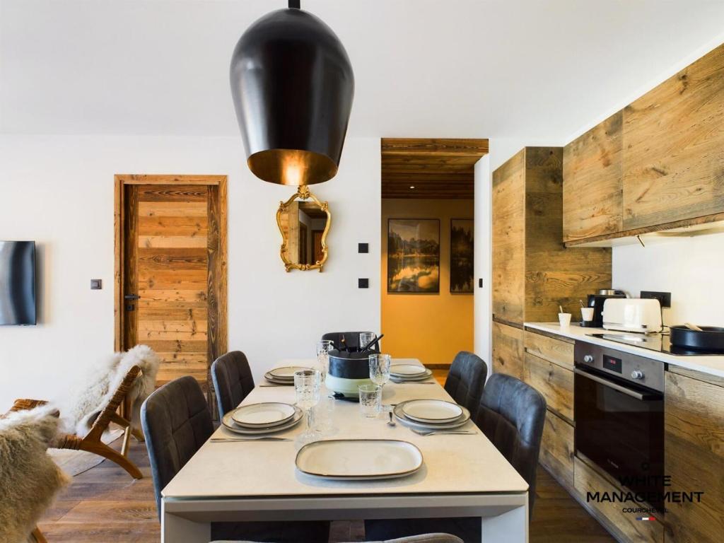 une cuisine avec une table et des chaises et une cuisine avec une cuisinière dans l'établissement Résidence Ariondaz Heliantheme - Superbe 3 pièces cabine proche des pistes MAE-4824, à Courchevel