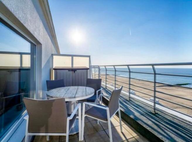 a balcony with a table and chairs and a view of the ocean at Studio Zeevonk Panoramic Sea View in Wenduine