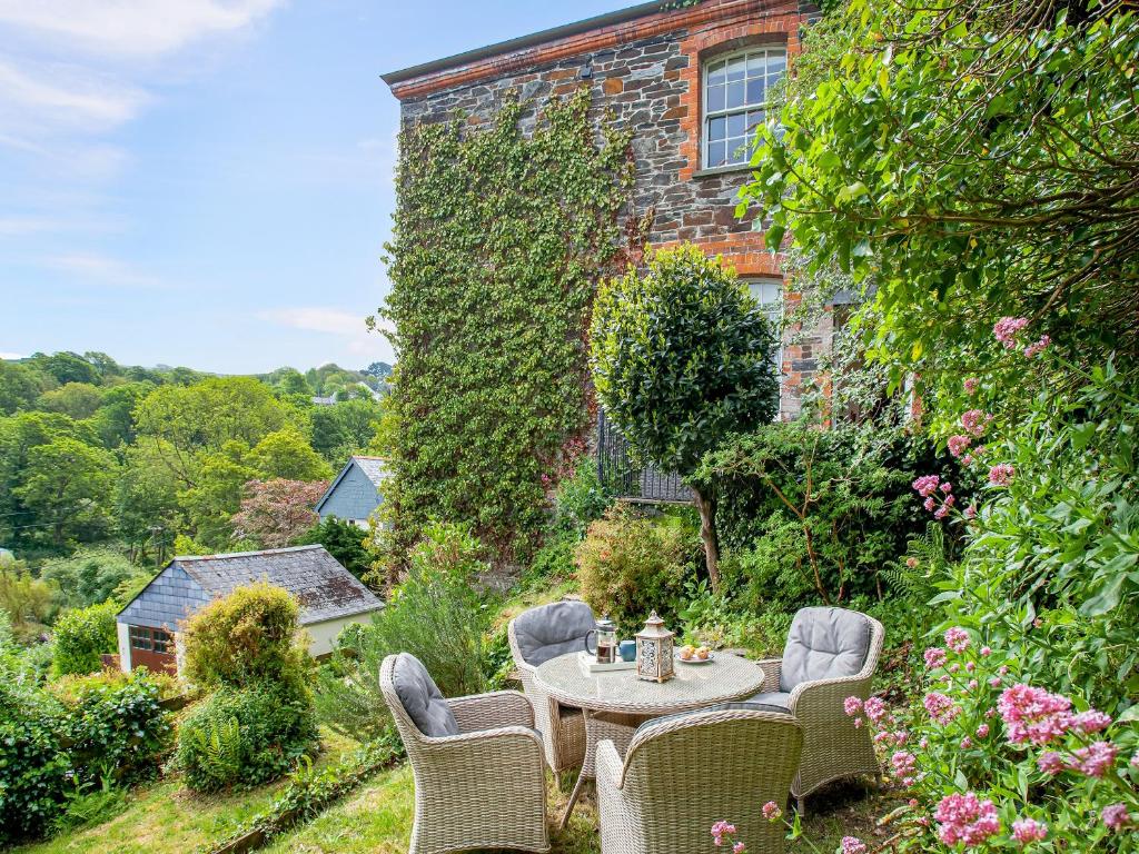 a table and chairs in a garden in front of a building at Lynwood in Boscastle