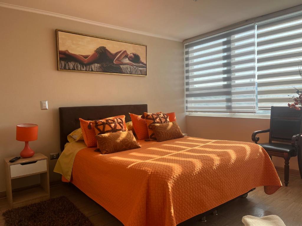 a bedroom with a bed with an orange blanket and a window at Depto 1 Dormitorio Centro Blanco 702 estacionamiento in Temuco