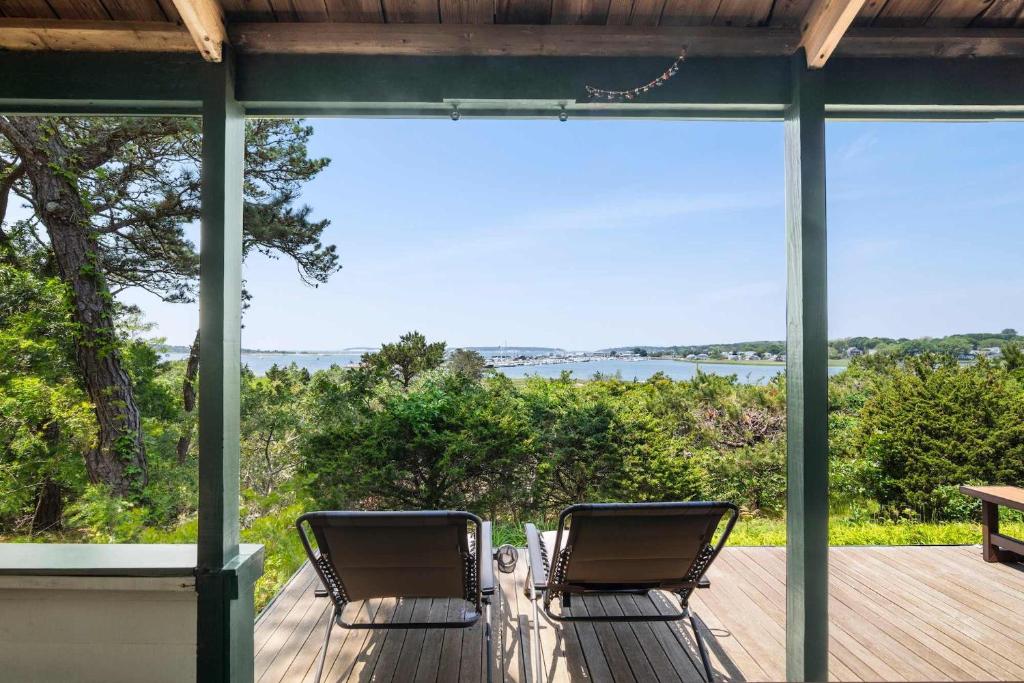 two chairs on a deck with a view of the water at Stunning Water Views Sleeps 14 in Wellfleet