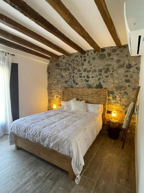a bedroom with a large bed with a stone wall at El Portalet de Can Rialla in Santa Pau