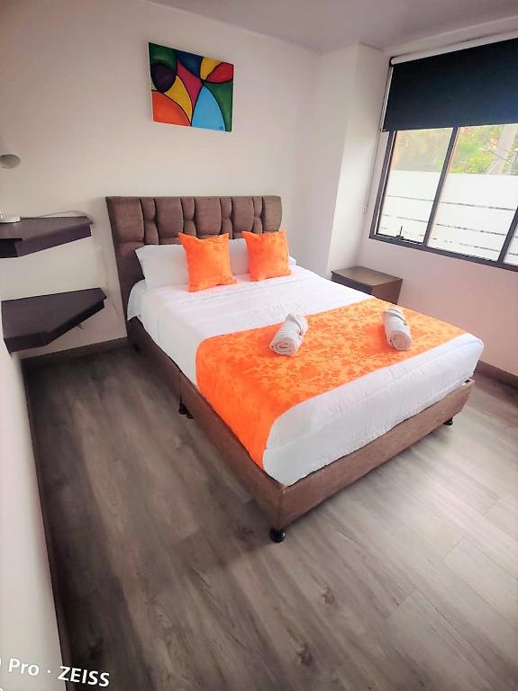 a bedroom with a large bed with orange pillows at Hotel Kristal Ferial in Bogotá