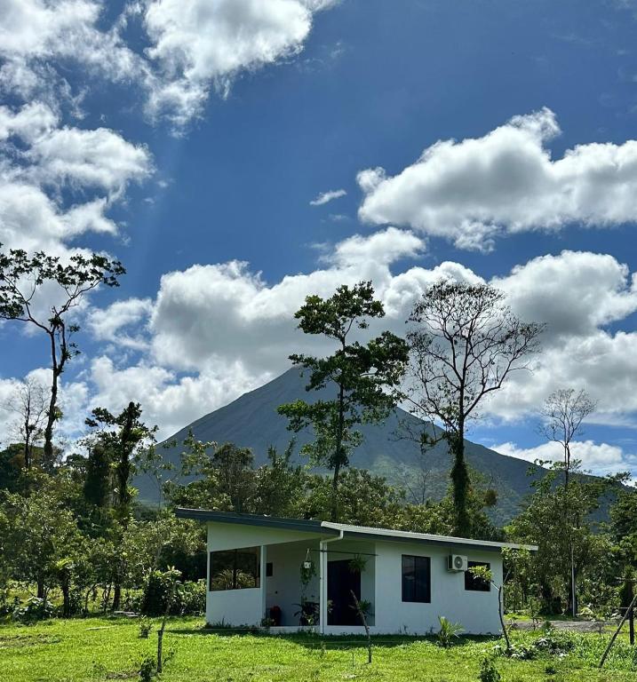 a small house in a field with mountains in the background at Casa Vista Arenal in Fortuna