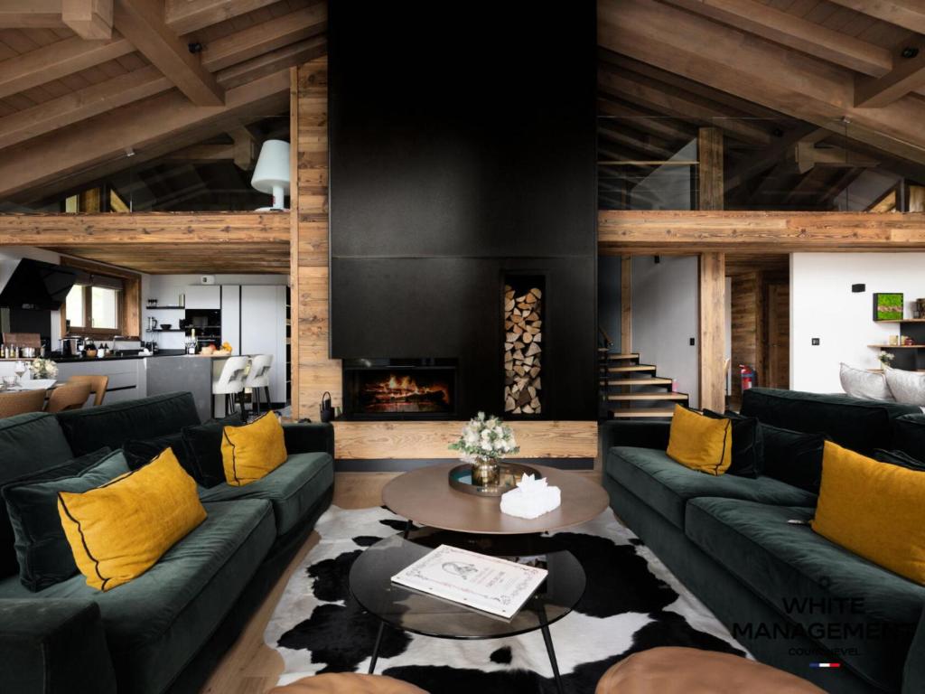 a living room with green couches and a fireplace at Résidence Canyon Lodge - Chalet d'exception dans le quartier du Belvédère MAE-2454 in Courchevel