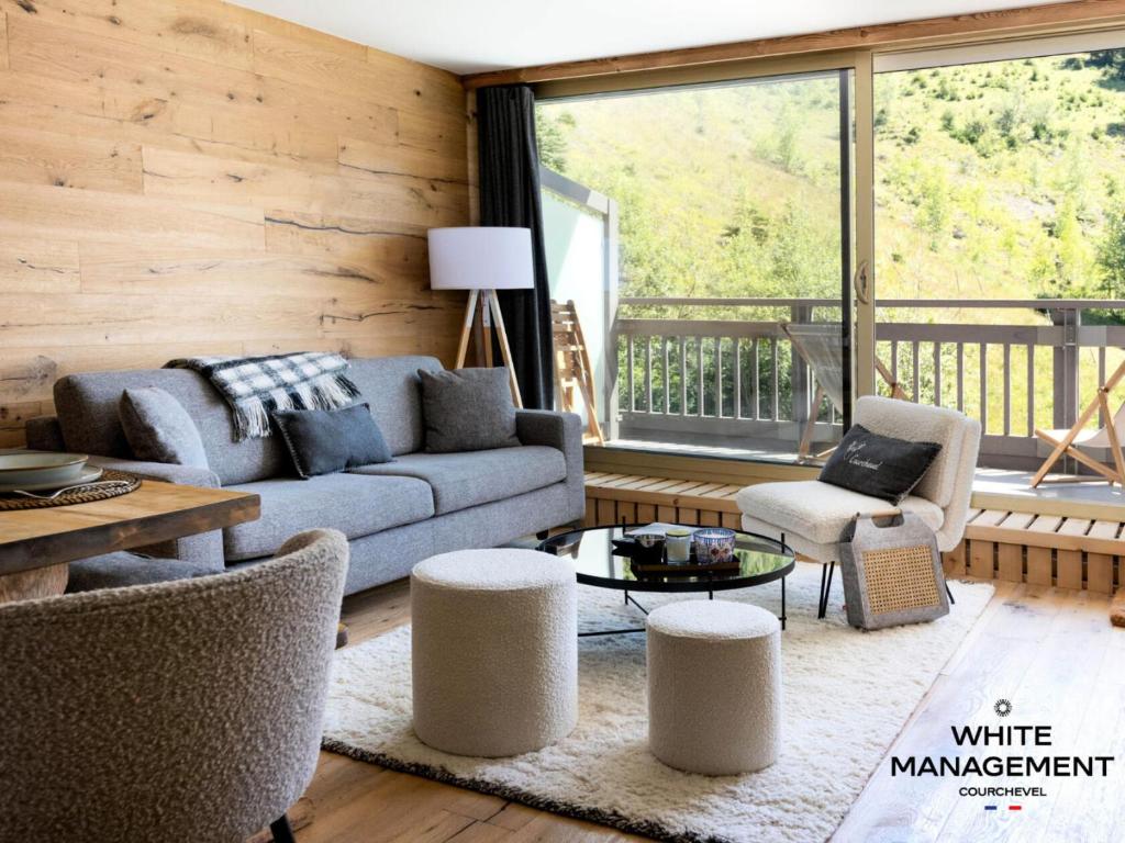 un salon avec un canapé et des chaises et une grande fenêtre dans l'établissement Résidence L'ourse Bleue - Appartement familial rénové au pied des pistes MAE-8344, à Courchevel