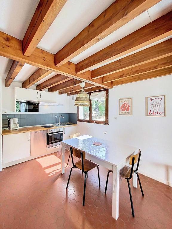 - une cuisine avec une table blanche et des chaises dans l'établissement Résidence Les As - Maisonnette 5 personnes, coté forêt à Lacanau Océan (sud) MAE-0281, à Lacanau