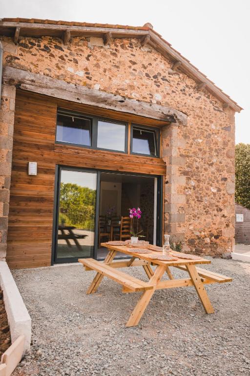 a wooden picnic table in front of a brick building at Grange Les Sens Ciel in Saint-Mesmin