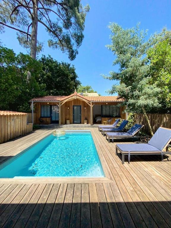 - une piscine sur une terrasse en bois avec des chaises longues dans l'établissement Résidence 03280-lacanau - Proche du lac magnifique cottage avec piscine privée pour 7 personnes MAE-0491, à Lacanau