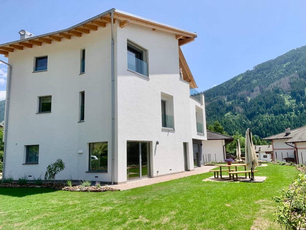 una grande casa bianca con un cortile verde di Sognatrentino a Cialini