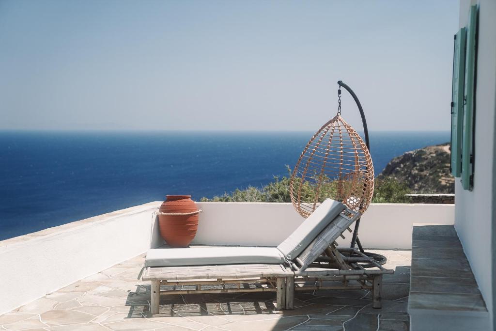 a rattan chair sitting on a patio overlooking the ocean at Xrisopigi Moonlight House Sifnos in Chrisopigi
