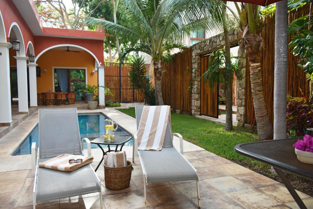 a patio with two chairs and a table next to a pool at VILLA UNAHANA in Valladolid