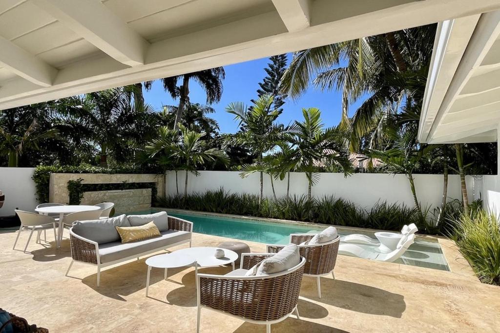 Un patio con sillas y mesas y una piscina. en Golf Villa V, en La Romana