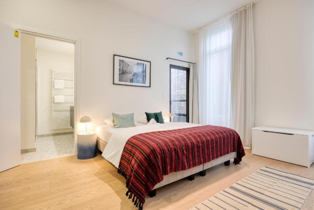 a bedroom with a large bed and a large window at The Ghentian Suites by Domani Hotels in Ghent