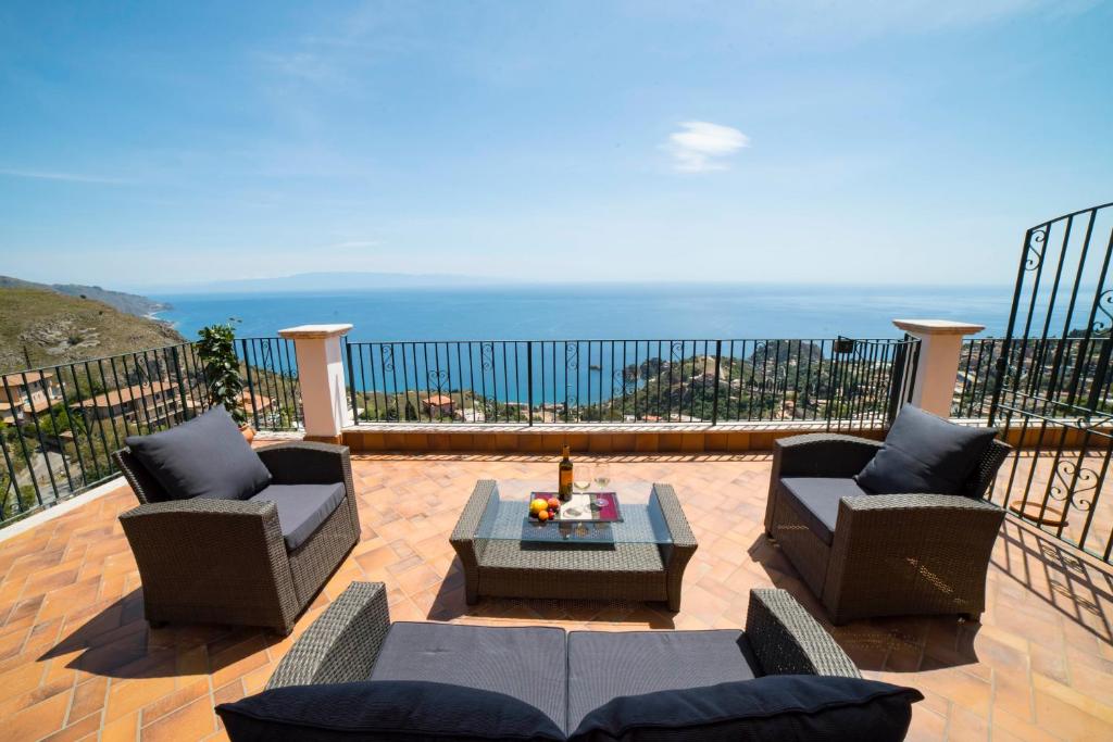 een patio met 2 stoelen en een tafel en de oceaan bij Villa Sofia in Taormina