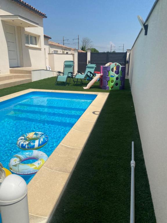 une cour avec une piscine et une aire de jeux dans l'établissement villa 8 personnes clim, piscine, parking, à Piolenc
