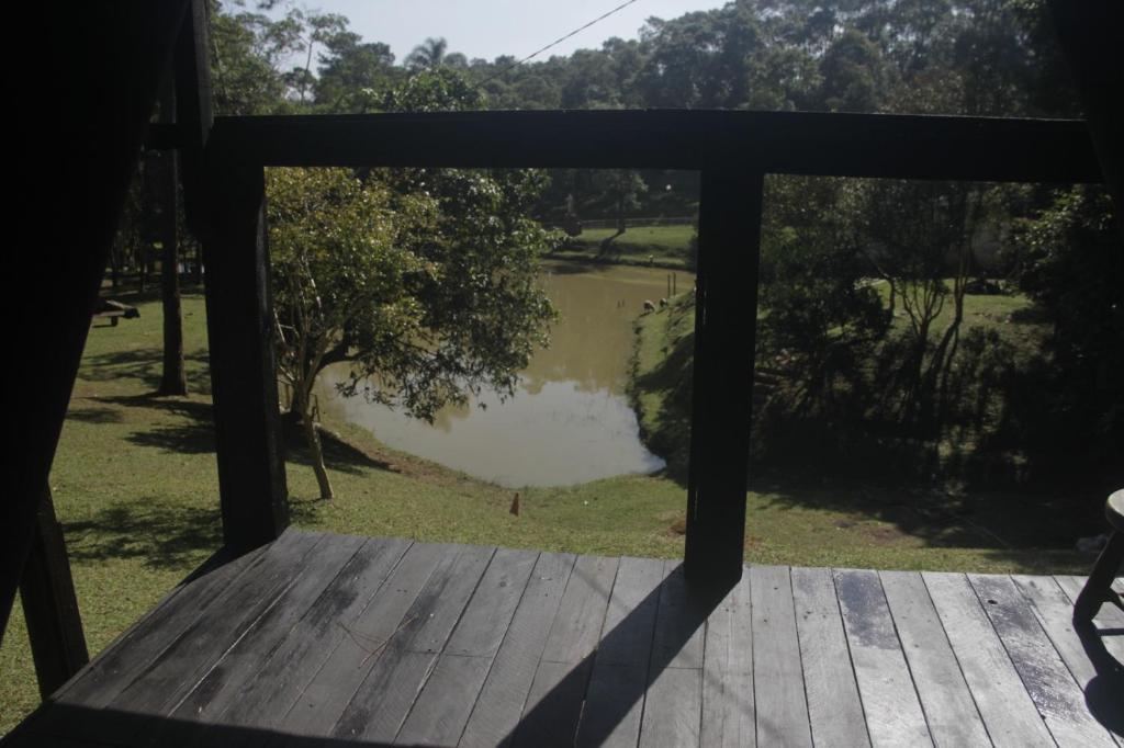 vistas a un estanque desde el porche de una casa en Chalé Hospedagem Ecológica, en Ribeirão Pires