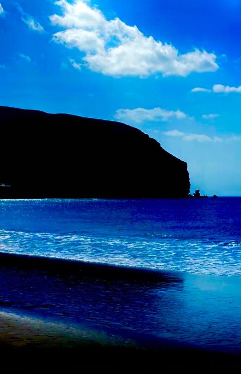 a beach with the ocean and a hill in the background at Paris Lovely in Gran Tarajal
