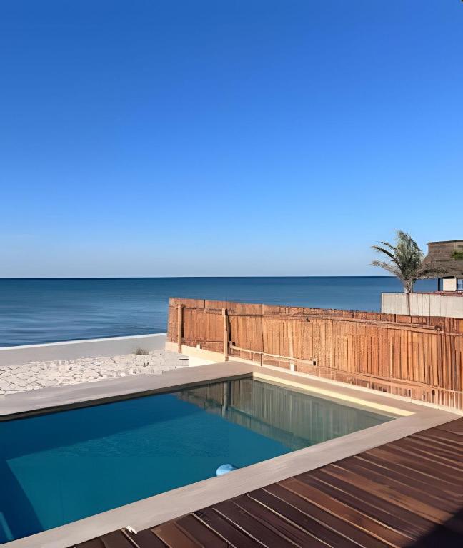 a swimming pool on the beach with the ocean in the background at Casa Mori frente al mar in San Benito
