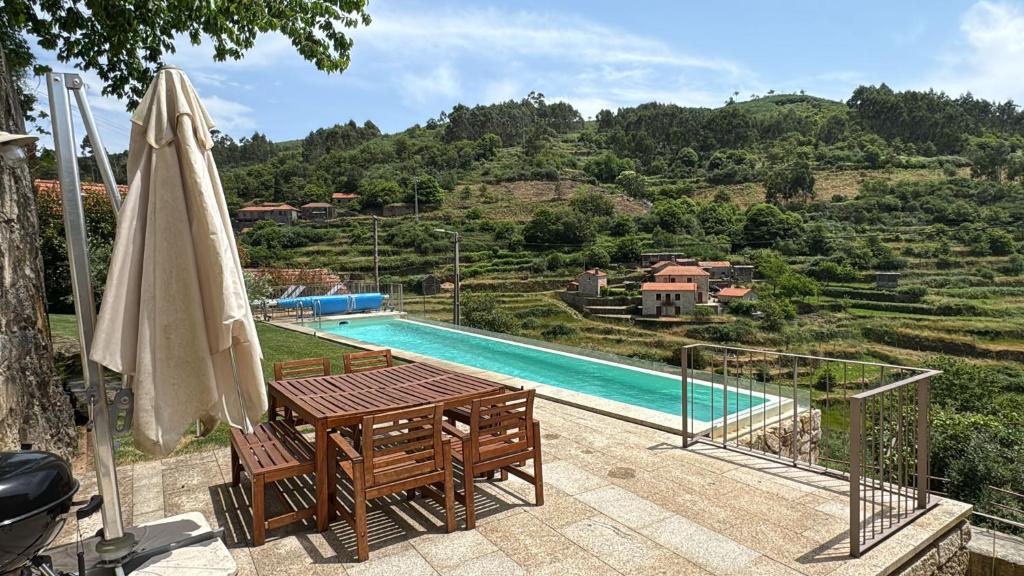 un patio con mesa, sombrilla y piscina en Casa da Gueira, en Vale de Cambra