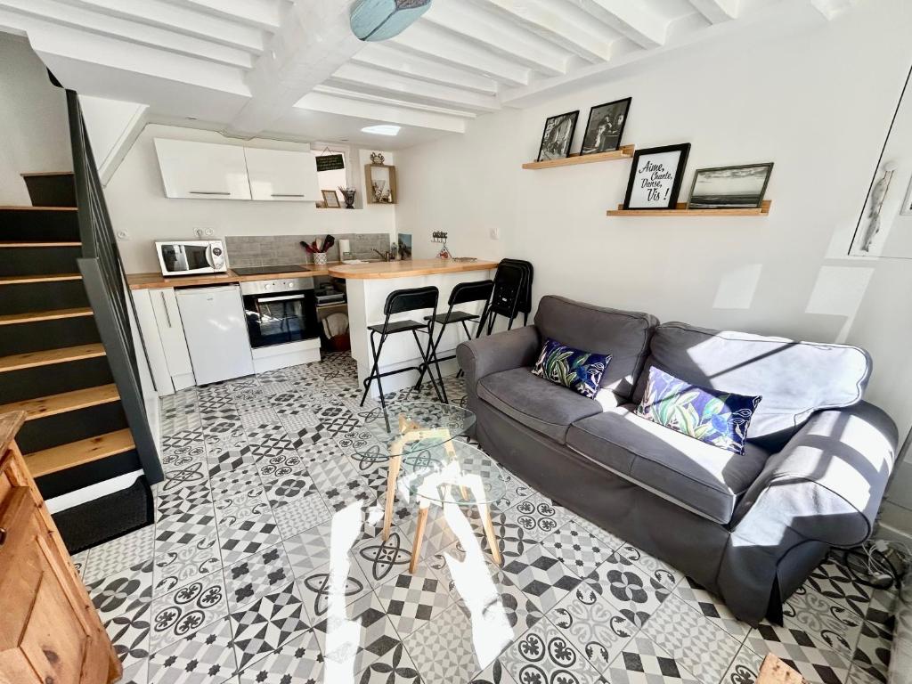 a living room with a couch and a kitchen at Charmante maison au coeur de Villerville in Villerville